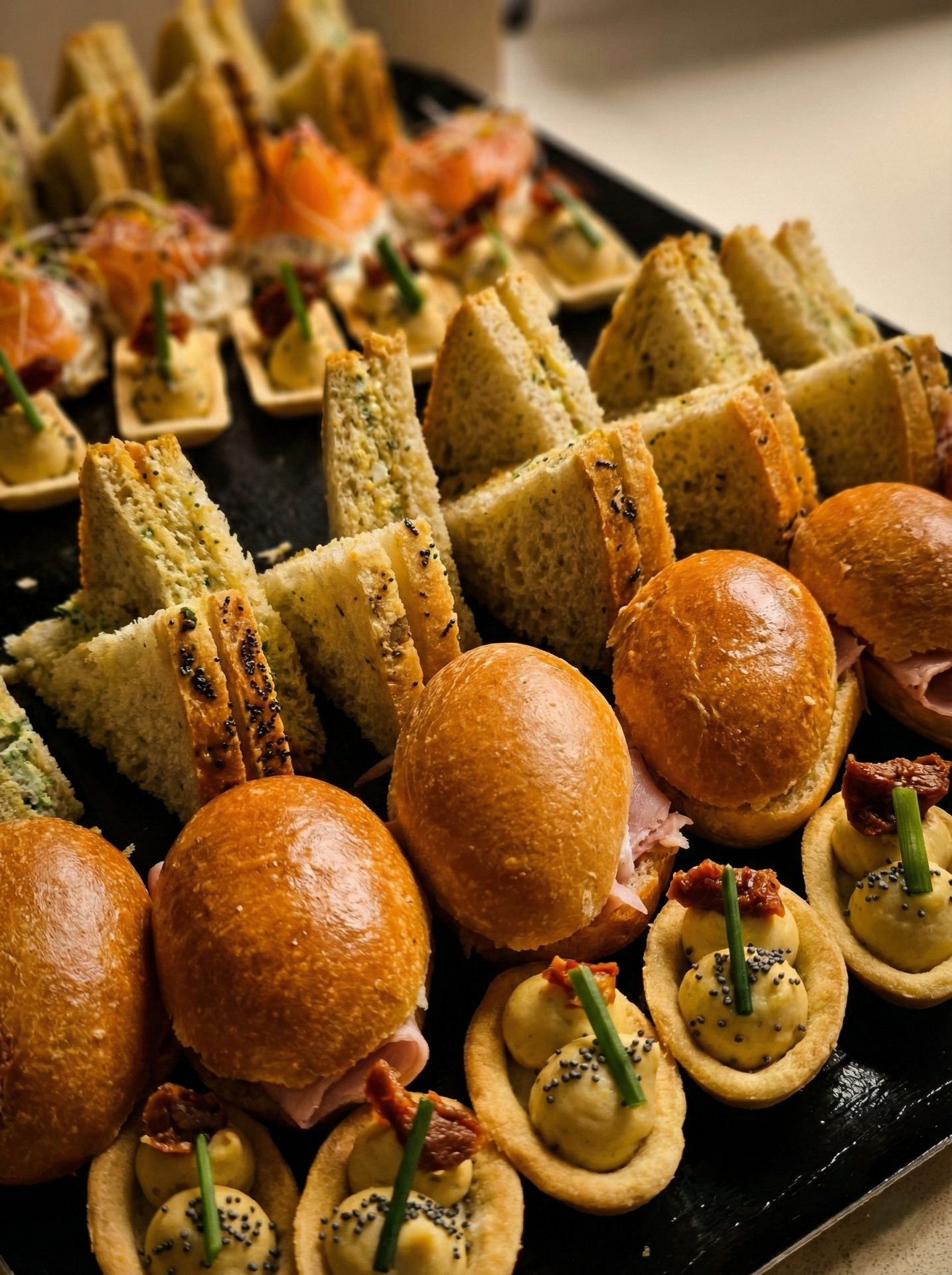 Plateau traiteur avec mini sandwichs briochés, sandwichs triangles et tartelettes salées.